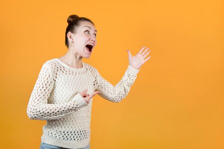 the girl screams at someone, actively gesturing. Isolated on orange yellow background.の写真素材