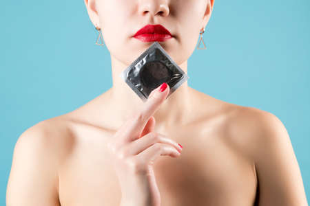 The girl holds a condom near her face. Close-upの写真素材