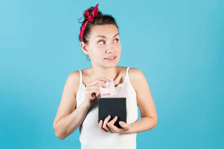 Girl puts or takes euro from savings box on a blue backgroundの写真素材