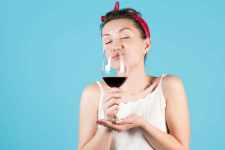 Close-up of a girl with a glass of wine on a blue backgroundの写真素材