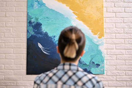 The view from the back of the girl who is looking at the picture in the gallery. Exhibition of the artistの写真素材