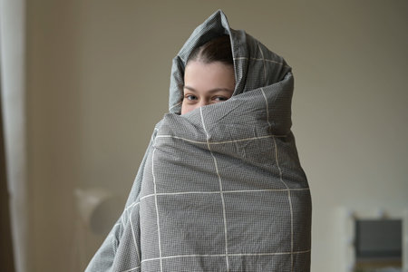 smiling and funny woman wrapped in a blanket in the morning after waking up. Weekend joys