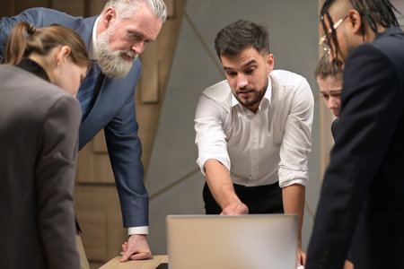 Office workers of different ages and nationalities are amicably discussing work matters. Brainstorming in a small firmの写真素材
