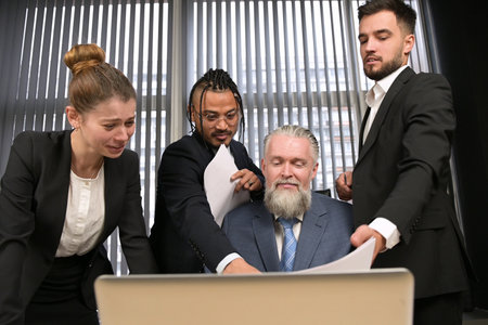 Colleagues amicably and actively discuss matters in the office of their manager. A gray-haired and respectable man listens to the opinions of his subordinates and discusses casesの写真素材