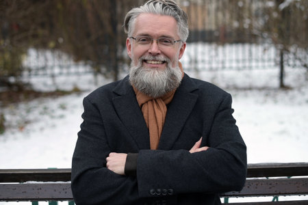 Close-up portrait of an adult solid gray-haired man with a beard wearing glassesの写真素材