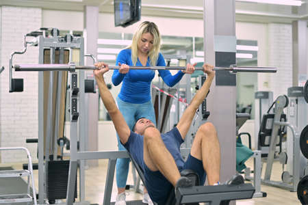 skinny guy does bench press under the supervision of a trainer, closeupの写真素材