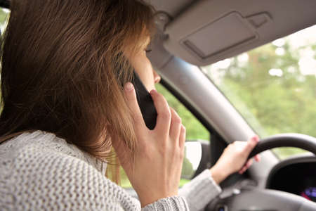 The woman answers the phone while driving. Driver creates danger by talking on the phone while drivingの写真素材