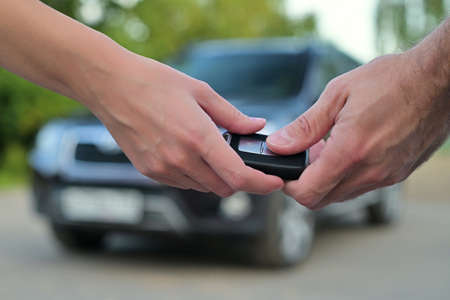 Woman and man pass the key to each other on the background of the car, close upの写真素材