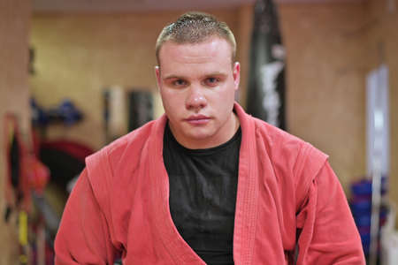 Young mma fighter in red kimono looks calmly at the cameraの写真素材