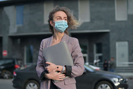 A young woman in a medical mask stands with documents in her handsの写真素材