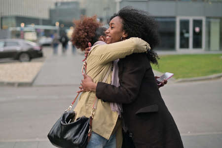 Two young black women hugging on the streetの写真素材
