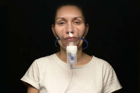 Young woman treats lungs and respiratory tract with an inhalerの写真素材