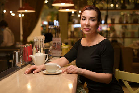 Portrait of a young beautiful woman at the bar who drinks teaの写真素材