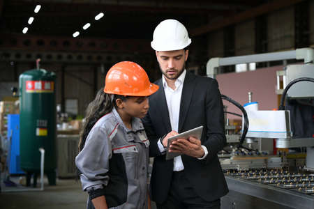 A young leader of the conveyor belt discusses work processes with a female workerの写真素材