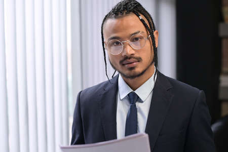 Young black man, extraordinary office employee looks into the camera