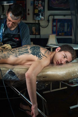 Tattooed man lying on the table in tattoo studioの写真素材
