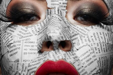 Beautiful girl with big Eyelashes, pink Lips and Newspaper on her Faceの写真素材