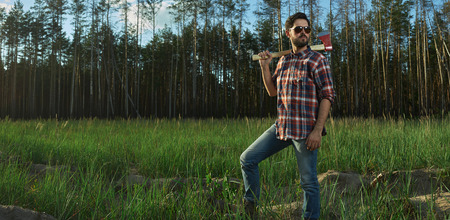 Serious Lumberjack with Sunglasses and big Axe on Shoulder in a Forestの写真素材