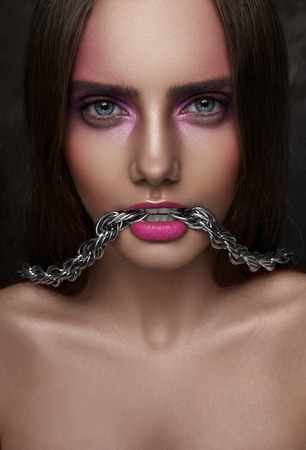 Fashion beauty Girl with Chain in her Mouth and shiny perfect Skinの写真素材