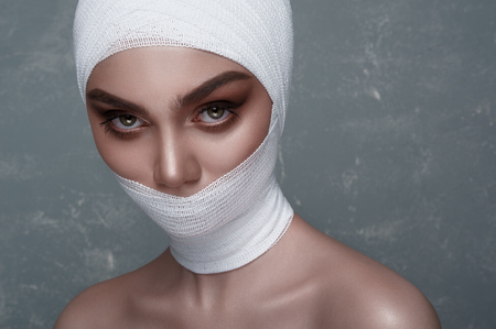 Beauty Girl with big Eyes and white Bandage on her Head and Mouthの写真素材