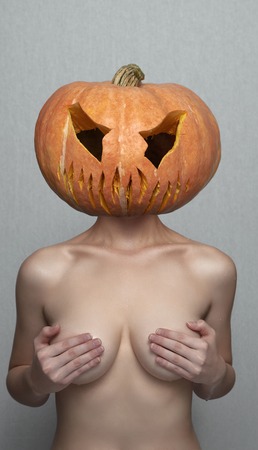 Sexy Woman with Halloween Pumpkin Head covers her Breastsの写真素材