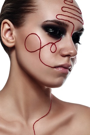 Beauty fashion Woman with red Thread on her Faceの写真素材