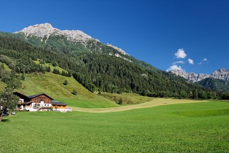 Rural landscape in Austrian Alps: green meadows under mountainsの写真素材