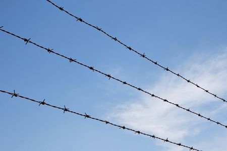 Three strands of rusty barbed wire over sky with cloudsの写真素材
