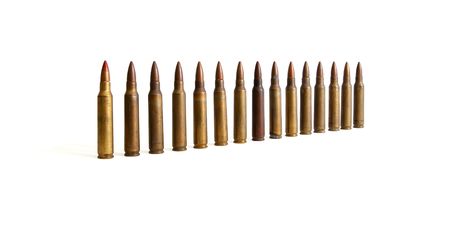 Row of standing M16 cartridges converging in perspective isolated