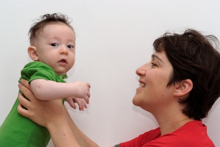 Cute baby held by his smiling mother looks toward the cameraの写真素材