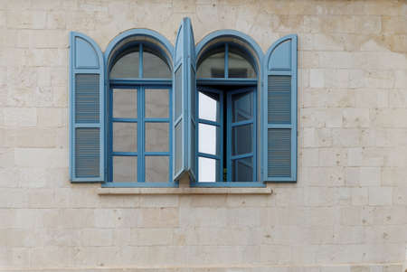 Open windows of the stone building with blue frame and blue wooden blindsの写真素材