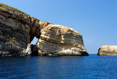 Scenic rocks with a hole near Gozo island on Malta, on bright summer dayの写真素材