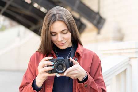 Close up of a charming brunet woman checking her fresh made picture on the camera standing outside...