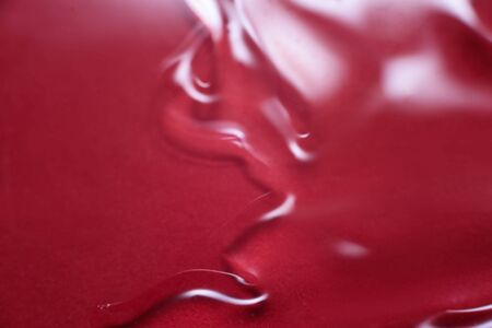 Abstract texture. Liquid gel cosmetics with little bubbles. Red background. Face cream. Close-up. Cosmetics product.の写真素材