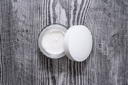 Opened jar of facial cream on the wooden background. Nature skin care.の写真素材