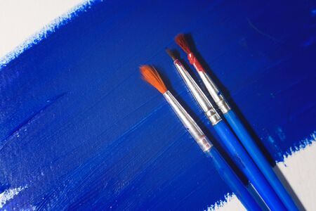 Blue colored paper with three brushes on it. Abstract background for your projects.