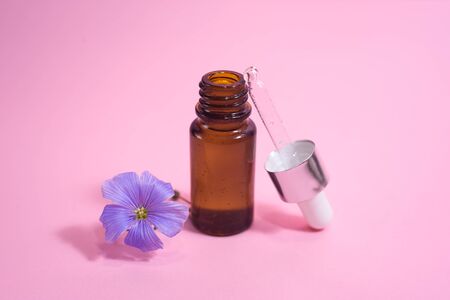 A glass dropper bottle with a pippette with white rubber tip and flower near it on the pink background. Nature Skin concept. Organic Spa Cosmetics. Close up.の写真素材