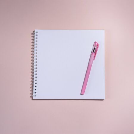 Opened book and pen on it on the pink background. Space for text. Top on view.の写真素材