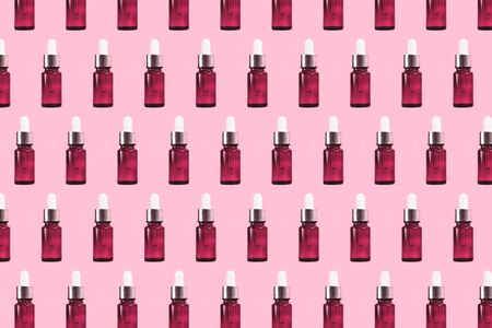 A glass dropper bottle with a pippette with white rubber tip and white jar of facial or body cream on the pink background. Nature Skin concept. Organic Spa Cosmetics. Close up.の写真素材