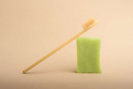 A bamboo toothbrush and a set of green handmade soap on the beige background. Natural hygiene...