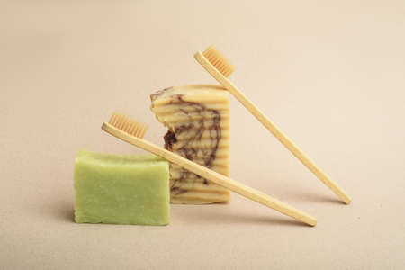 Two bamboo toothbrushes and two sets of handmade soap on the beige background. Natural hygiene...