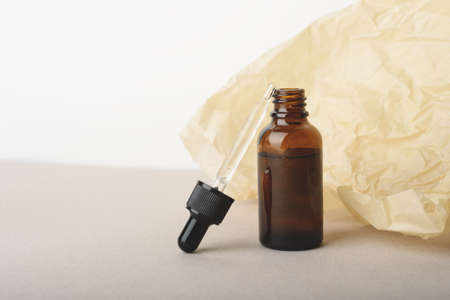 Serum glass bottle with pipette on the beige wrinkle paper background. Natural Organic Spa Cosmetic concept. Front view. Place for your text.の写真素材