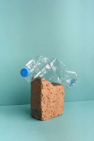 Used crushed plastic bottle on brick stone on the blue background. Recycling concept.