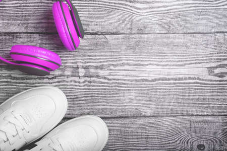 Flat lay with white sneakers and purple earphones on wooden background. Top view with space for your text.の写真素材