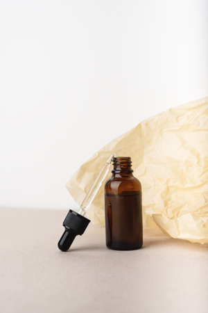 Serum glass bottle with pipette on the beige wrinkle paper background. Natural Organic Spa Cosmetic concept. Front view. Place for your text.の写真素材