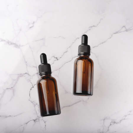 Glass dropper bottles with a pippette with black rubber tip on the beautiful white marble...
