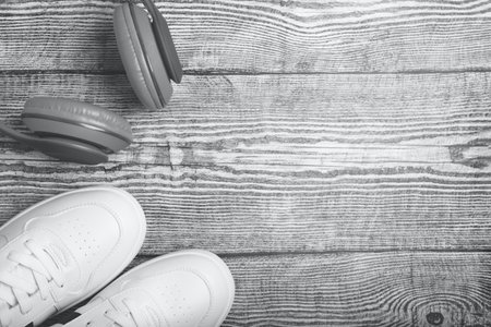 Flat lay with white sneakers and gray earphones on wooden background. Top view with space for your text.の写真素材