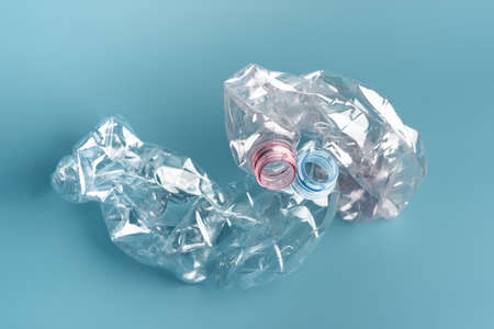 Two used crushed plastic bottles on blue background.