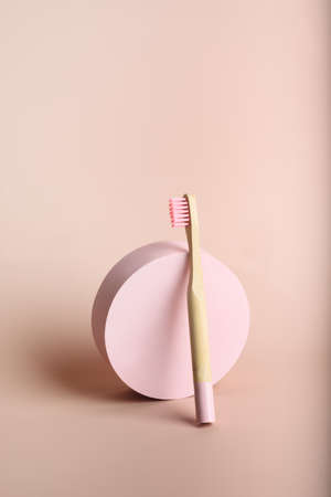 One eco friendly natural bamboo toothbrush near circle decor on pink background.の写真素材