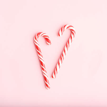 Christmas striped red and white heart shaped hard candies on pink background.の写真素材
